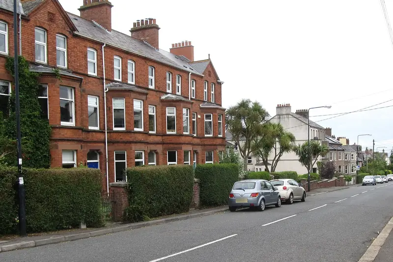 Tall red-brick Victorian terrace with bay windows and hedged front gardens